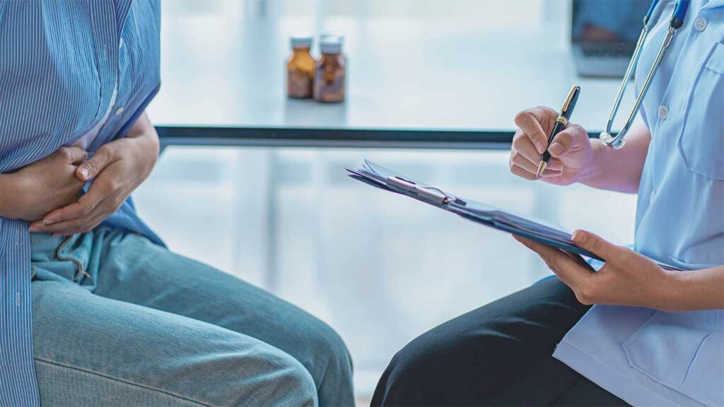 A doctor taking notes while a woman describes her menstrual pain and discomfort in a clinical setting. 