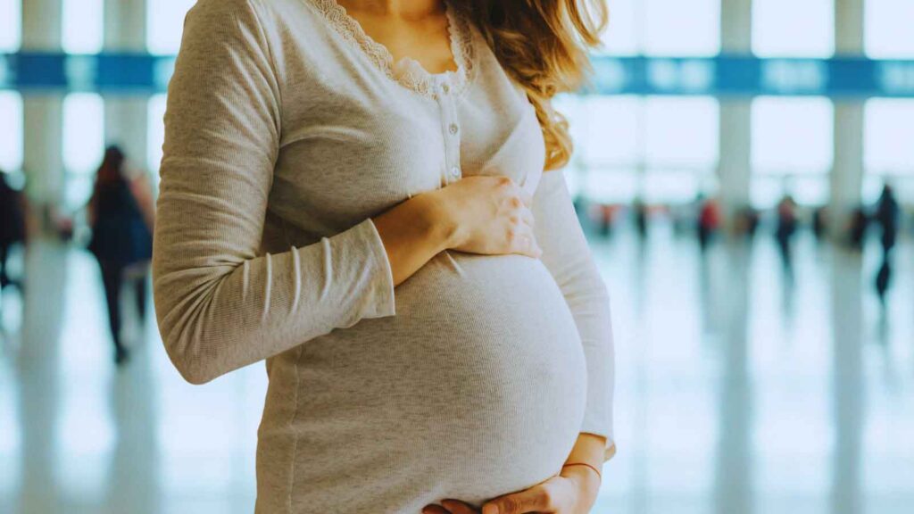 Pregnant woman standing in airport terminal during travel and pregnancy. 