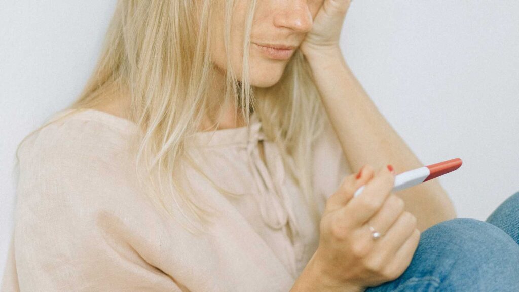 Woman holding test device while looking concerned, considering at-home STD test kits for private health screening 