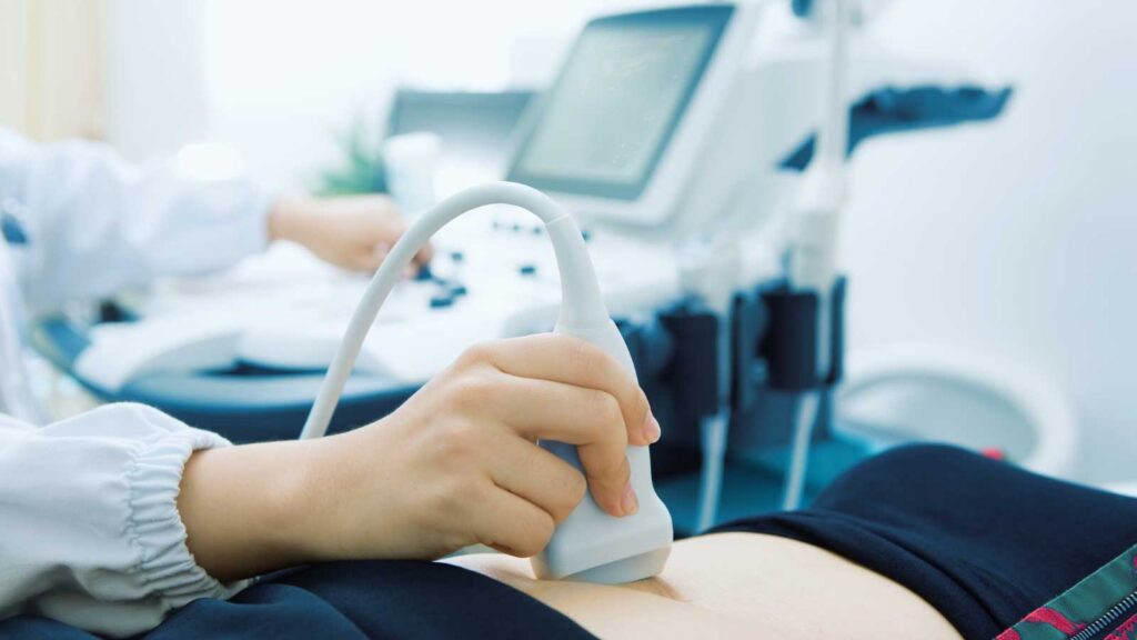 A doctor performing an abdominal ultrasound on a patient during a routine OBGYN checkup. 